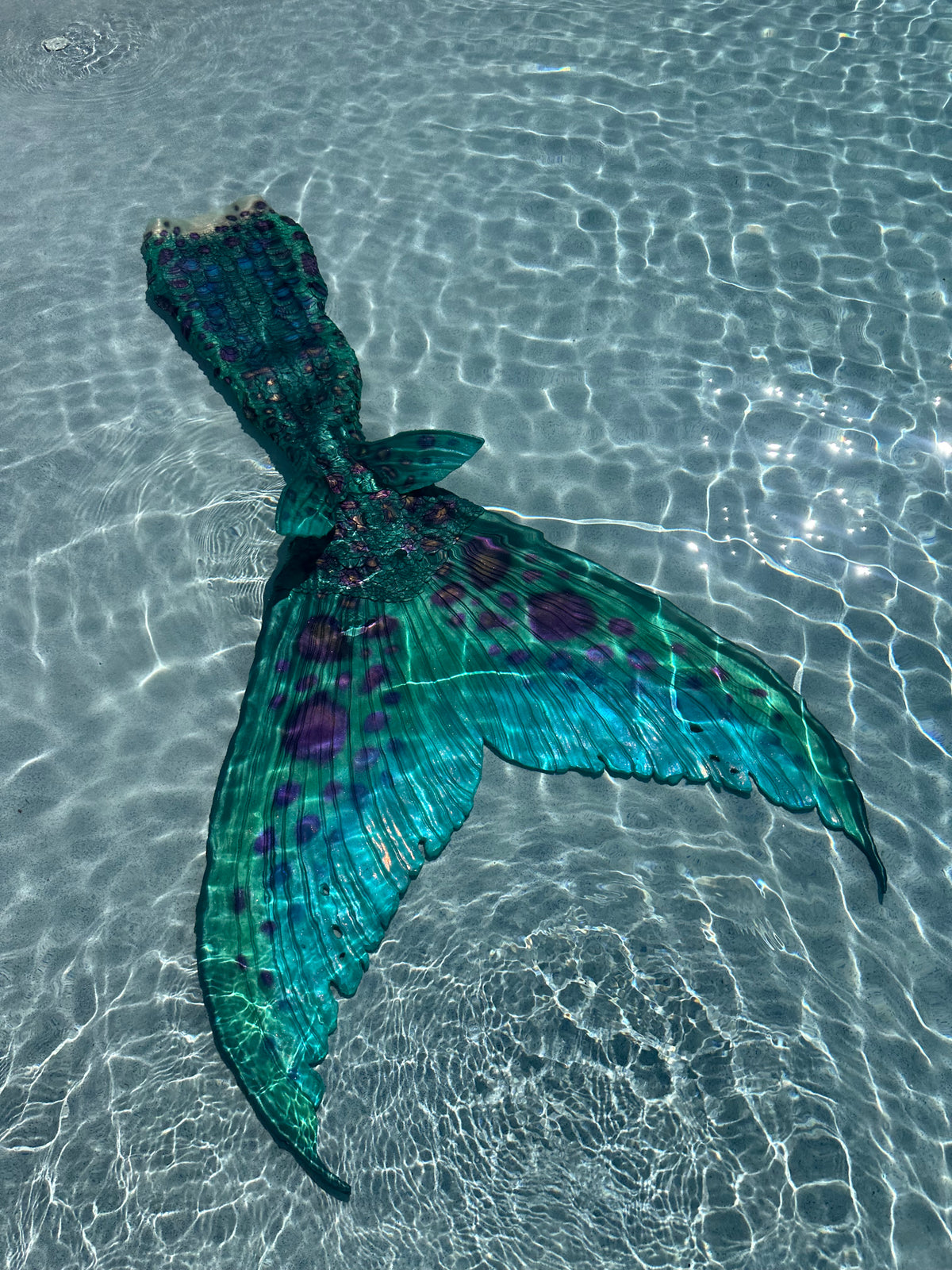 Teal custom silicone mermaid tail with realistic fluke and fin details underwater